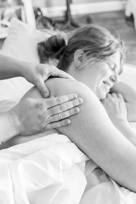 A black and white photo of Deandra working on her prenatal client's shoulder